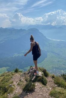 Susanna Tapani standing on a rocky mountain peak, overlooking a scenic valley.