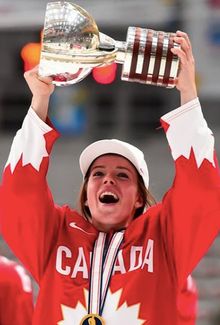 Victoria Bach holding up a hockey trophy in front of a crowd.