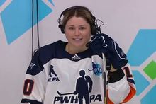 Sam Isbell wearing a headset while being interviewed in her hockey gear between periods