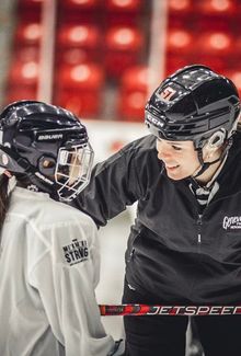 Victoria Bach leaning over coaching a little girl face to face.