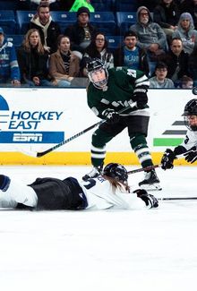 Hannah Brandt (PWHL Boston) attempting to lift the puck over a defender lying on the ice