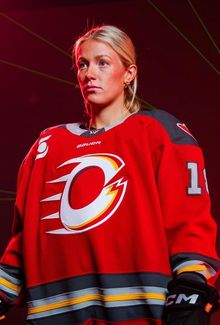 Mannon McMahon in a Ottawa Charge jersey, standing confidently against a dark red background.