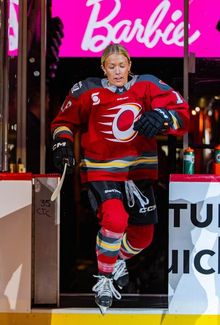 Mannon McMahon steps onto the ice from the bench, with a "Barbie" sign in the background.