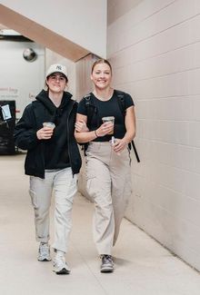 Michela Cava and friend walking in a hallway, both holding iced coffee.