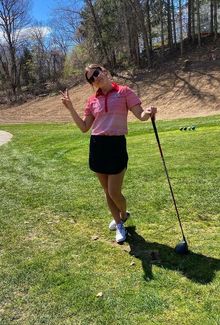 Kennedy Marchment posing at the tee box on the golf course throwing up a peace sign