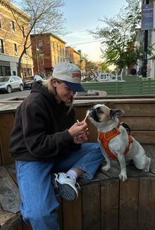 Sam Isbell sitting on a bench with her dog while she feeds the dog ice cream