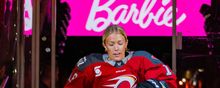 Mannon McMahon steps onto the ice from the bench, with a "Barbie" sign in the background.