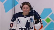 Sam Isbell wearing a headset while being interviewed in her hockey gear between periods