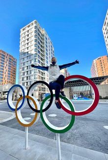 Emma Soderberg sitting on top of an olympic ring in front of buildings.